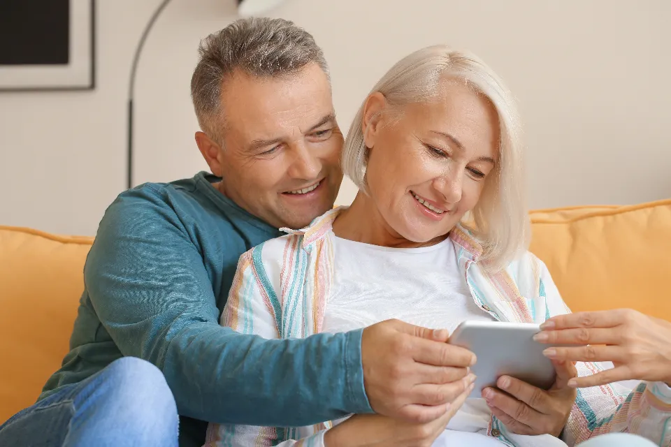 A mature couple relaxing on the sofa and looking at a phone together