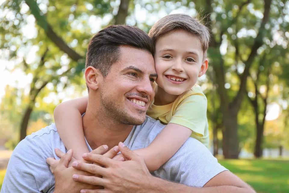 A father hugging his smiling son outdoors