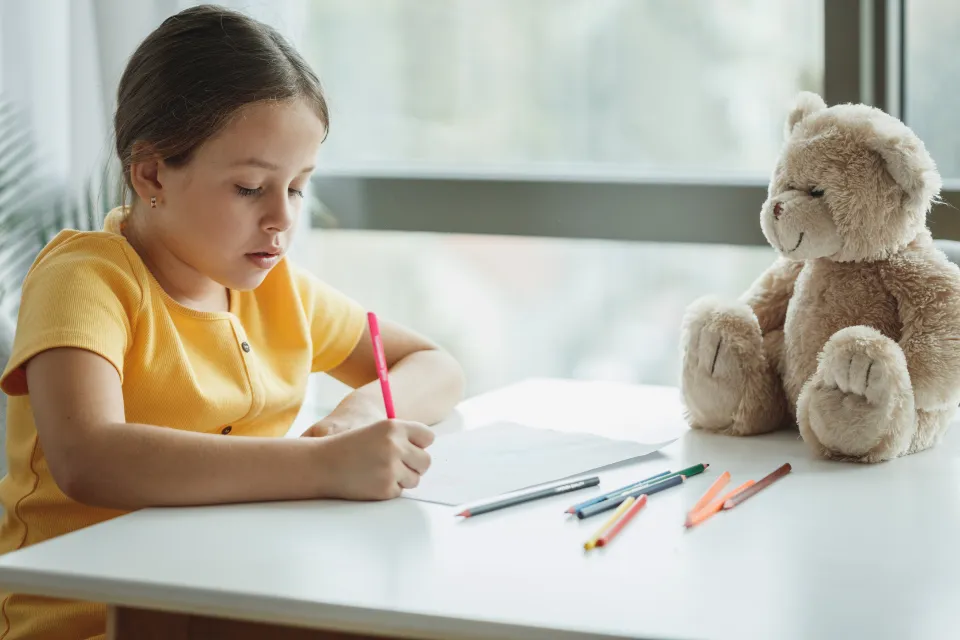 A young girl drawing at her desk