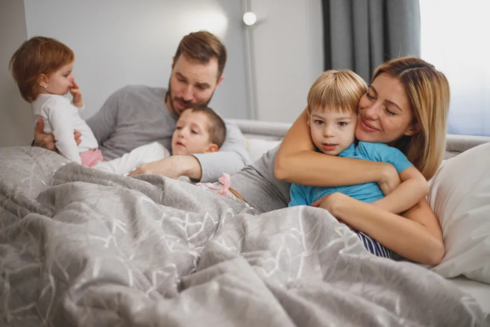 Parents relaxing in bed with their two young children