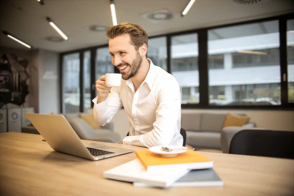 A smiling professional working on a laptop in a bright office
